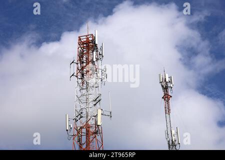 Mobile Telekommunikationstürme am blauen Himmel mit weißen Wolken. Mobilfunkturm mit Antennen und elektronischen Kommunikationsgeräten Stockfoto