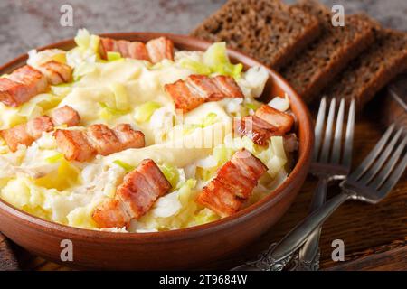 Traditioneller norwegischer Plukkfisk gedünsteter Fisch mit Kartoffelpüree, garniert mit leckerem Speck aus nächster Nähe auf einem Teller auf dem Tisch. Horizontal Stockfoto