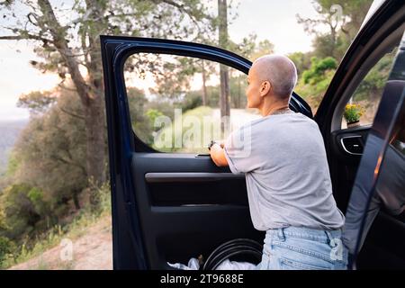 Frau, die sich auf ihren Van lehnt und die Landschaft bewundert Stockfoto