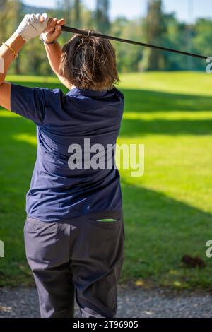 Golferin macht einen Golf Swing an einem sonnigen Tag in der Schweiz Stockfoto