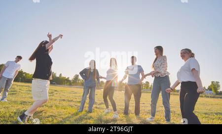 Lustige Freunde, die abends auf der Wiese der Stadt tanzen. Stockfoto
