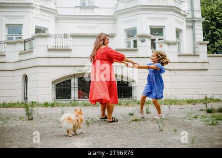 Mama und Tochter in hellen Kleidern drehen sich und haben Spaß am Sommertag im Park. Positiv. Stockfoto