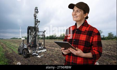 Der Landwirt steuert einen autonomen Roboter zur Messung der Bodenqualität auf einem landwirtschaftlichen Feld. Smart-Farming-Konzept. Stockfoto