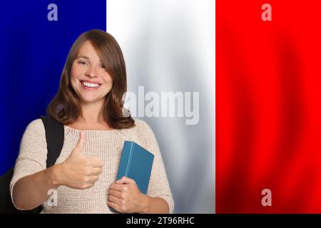 Glückliche Studentin vor französischem Flaggenhintergrund. Reisen, Bildung und Sprachenlernen in Frankreich Konzept Stockfoto