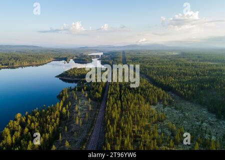 Aus der Vogelperspektive auf den Fluss und die Straße, die durch Wälder und Berglandschaften in Nordschweden verlaufen Stockfoto