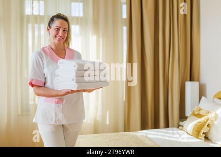 Porträt eines wunderschönen Zimmermädchens mit sauberen und frischen Handtüchern. Stockfoto