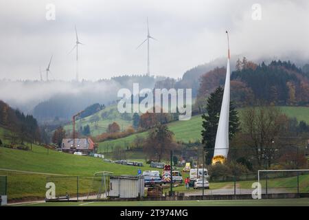23. November 2023, Baden-Württemberg, Biberach: Auf einem sogenannten selbstfahrenden Transporter wird ein Windenergieschaufel montiert und durch das Dorf Prinzbach transportiert, während andere Windenergieanlagen im Hintergrund zu sehen sind. Insgesamt sollen drei 68 Meter lange Rotorblätter aus Biberach über eine Entfernung von rund sieben Kilometern transportiert werden. Nach Angaben des Energieversorgers Badenova sind millimetergenaue Arbeiten erforderlich, um sicherzustellen, dass die Rotorblätter die Baustelle unbeschädigt erreichen. An einigen Stellen entlang der Strecke muss eine Steigung von 12 Prozent gemeistert werden. Foto: Philipp Stockfoto