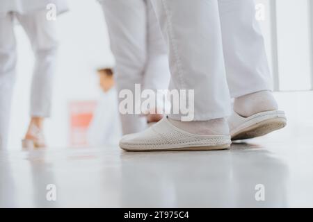 Erfahrener Doktor steht selbstbewusst im Krankenhausflur mit medizinischer Uniform und weißen Schuhen. Stockfoto