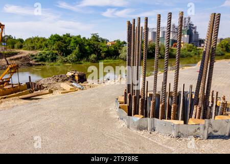 Oberteil, Ankerstangen, der Verstärkung von der Betonsäule im Sockel. Mobiler Kran, Brückenfundament mit Metallpfählen im Hintergrund Stockfoto