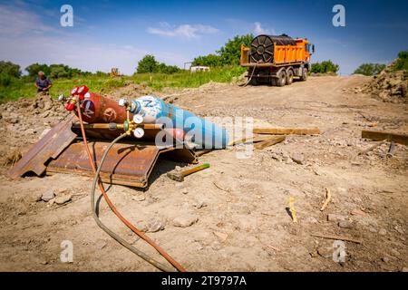 Rote und blaue Schweißgeräte, Sauerstoff- und Stickstofftanks mit Ventilen und Manometern, Acetylengaszylinder auf Metallstapeln im Gebäude Stockfoto