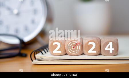 Holzblöcke mit den Buchstaben 2024 mit Kalender und Wecker auf hölzernem Hintergrund, die den Übergang zu 2024 darstellen, Business Startup Plan, The Cou Stockfoto