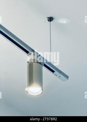 Eine elegante moderne Lampe hängt von der Decke und beleuchtet ein zeitgenössisches Keramikwaschbecken darunter Stockfoto