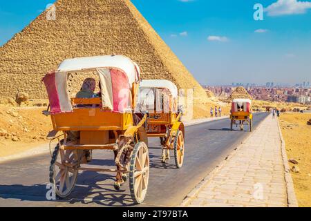 Pferdekutschen transportieren Touristen in der Nähe der Großen Pyramiden von Ägypten. Gizeh, Ägypten – 16. Oktober 2023 Stockfoto