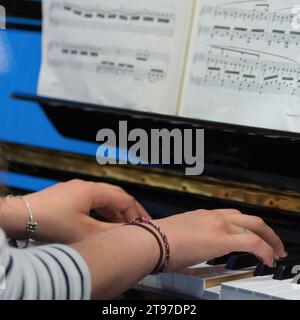 Menschliche Hände spielen während eines Pianolessons die Noten und Akkorde auf einem klassischen schwarzen Klavier Stockfoto