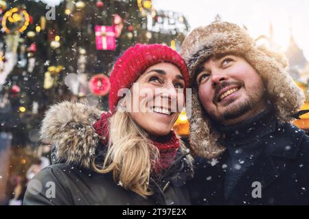 Glückliches Paar Touristen auf dem Weihnachtsmarkt vor dem Baum im Winter Stockfoto
