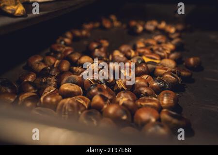 Geröstete Kastanien verteilt auf einem heißen Grill auf einem Weihnachtsmarkt Stockfoto