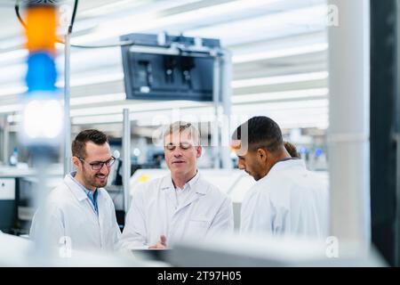 Techniker in Labormänteln diskutieren in der Elektronikfabrik Stockfoto