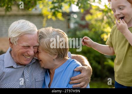 Glückliches älteres Ehepaar mit Enkel im Garten Stockfoto