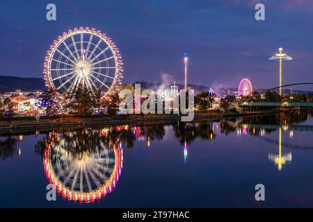 Deutschland, Baden-Württemberg, Stuttgart, Cannstatter Wasen, glühendes Riesenrad, das nachts im Neckar reflektiert Stockfoto