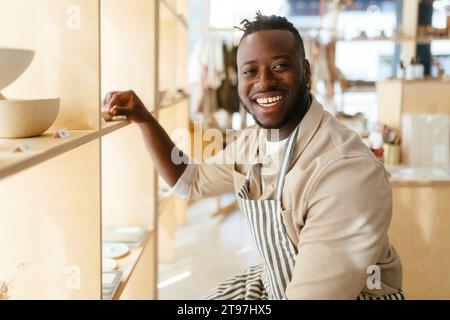 Glücklicher Besitzer, der die Produkte im Geschäft im Regal arrangiert Stockfoto