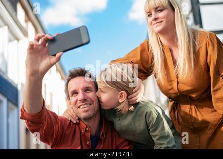 Ein lächelnder Vater macht Selfie mit der Familie über das Smartphone Stockfoto