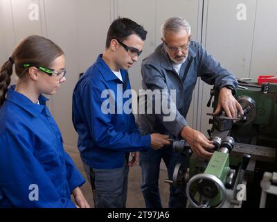 Kursleiter führt die Auszubildenden mit Drehmaschine in der Werkstatt Stockfoto