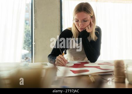 Blonde Künstlermalerei mit Pinsel im Atelier Stockfoto