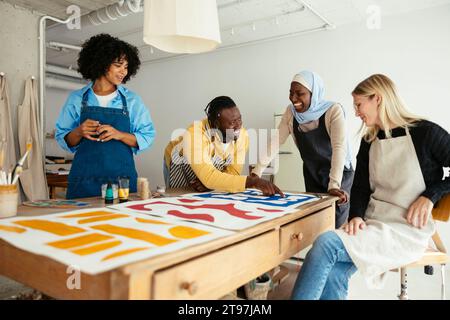 Lächelnde Künstler diskutieren über Gemälde auf dem Schreibtisch im Studio Stockfoto