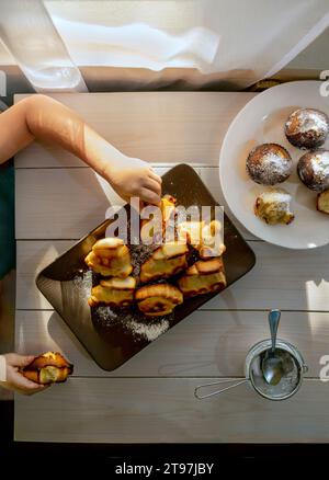 Hand eines Jungen, der Cupcakes vom Teller auf dem Tisch nimmt Stockfoto