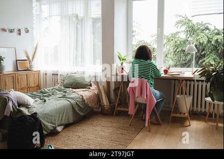 Mädchen macht Hausaufgaben am Schreibtisch im Schlafzimmer Stockfoto