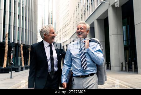 Fröhliche Geschäftsleute gehen und reden miteinander Stockfoto