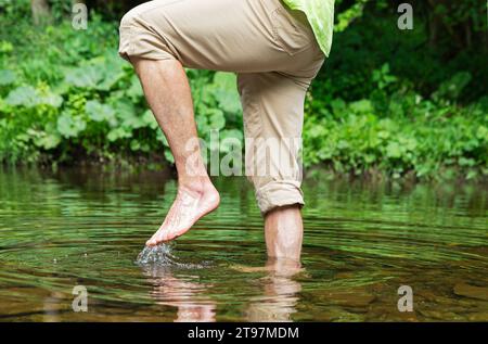 Senior Mann, der barfuß im Fluss läuft Stockfoto