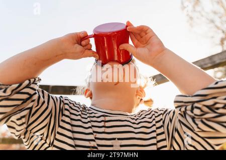 Mädchen trinkt heiße Schokolade an sonnigen Tagen Stockfoto