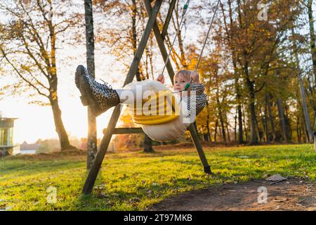 Mädchen, das auf dem Spielplatz im Park auf einer Schaukel schwingt Stockfoto