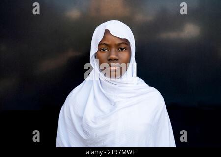 Ernsthafte junge Frau, die Hijab vor schwarzer Wand trägt Stockfoto