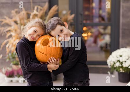 Glücklicher Bruder und Schwester halten geschnitzten Kürbis zusammen Stockfoto