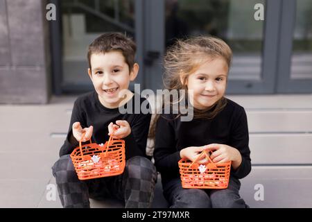 Bruder und Schwester halten Körbe für Halloween-Süßigkeiten Stockfoto