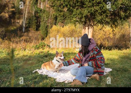 Junge Frau, die am Wochenende mit Hund auf Decke im Naturpark Handshake macht Stockfoto