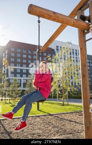 Mädchen spielt auf der Schaukel auf dem Spielplatz Stockfoto