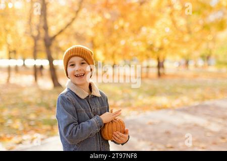 Ein lächelnder Junge hält Kürbis in der Hand im Herbstpark Stockfoto