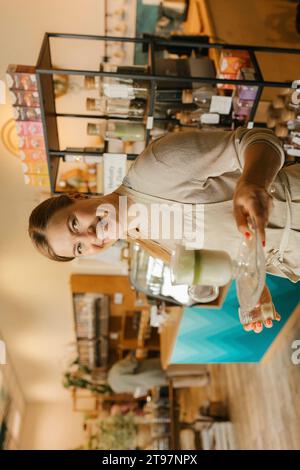 Lächelnder Kellner mit Matcha-Milchshake im Café Stockfoto