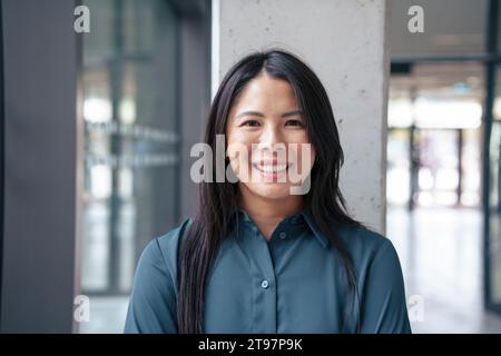 Glückliche Geschäftsfrau, die auf dem Flur steht Stockfoto