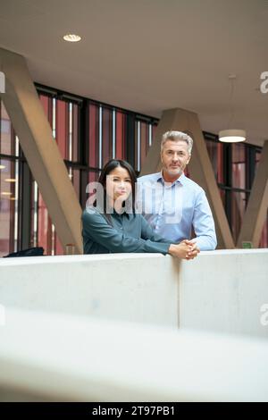 Lächelnde Geschäftsfrau, die mit Geschäftsmann in der Nähe der Mauer steht Stockfoto