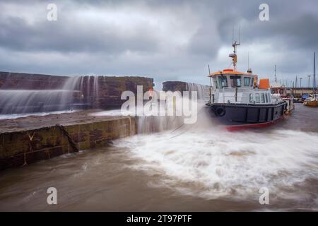 Großbritannien, Schottland, North Berwick, lange Zeit ausgesetzt von Wellen, die über die Hafenmauer vor dem Anlegeboot brechen Stockfoto