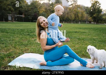 Mutter hält den Sohn in der Nähe des Hundes im Park Stockfoto