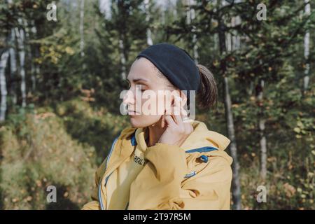 Frau, die Musik über kabellose in-Ear-Kopfhörer im Forest hört Stockfoto