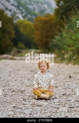 Mädchen sitzt mit geschlossenen Augen und meditiert vor Bäumen Stockfoto