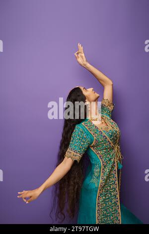 Vertikaler Schuss einer langhaarigen jungen indianerin in Nationalkostümen, während sie aktiv tanzt Stockfoto