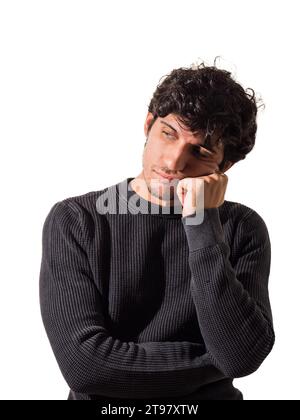 Ein Mann mit lockigen Haaren, der einen schwarzen Pullover trägt, denkt, enttäuscht oder traurig, im Studio Stockfoto