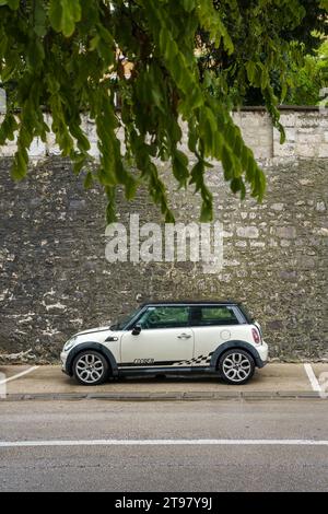 Weißer und schwarzer Mini Cooper parkte neben einer alten Steinmauer in Zadar, Kroatien. September 2023. Stockfoto